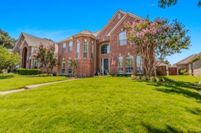 Angled street view of brick home with blooming crape myrtle