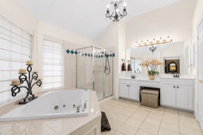 Primary bath with jetted corner tub, glass shower, and dual vanities