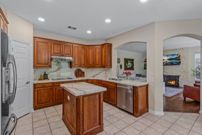 Kitchen with marble island and counters opening to fireplace living room