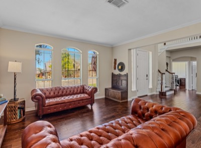 Formal living room with tufted leather sofas opening to front entry
