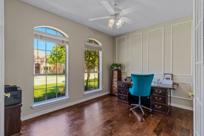 Home office with dark wood desk and arched front windows
