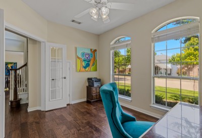 Office nook with teal chair beside staircase and street-view windows