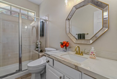 Guest bath with glass shower, marble vanity, and octagonal mirror