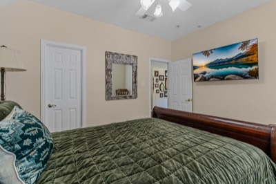 Bedroom with sleigh bed, green quilt, and mountain lake wall art